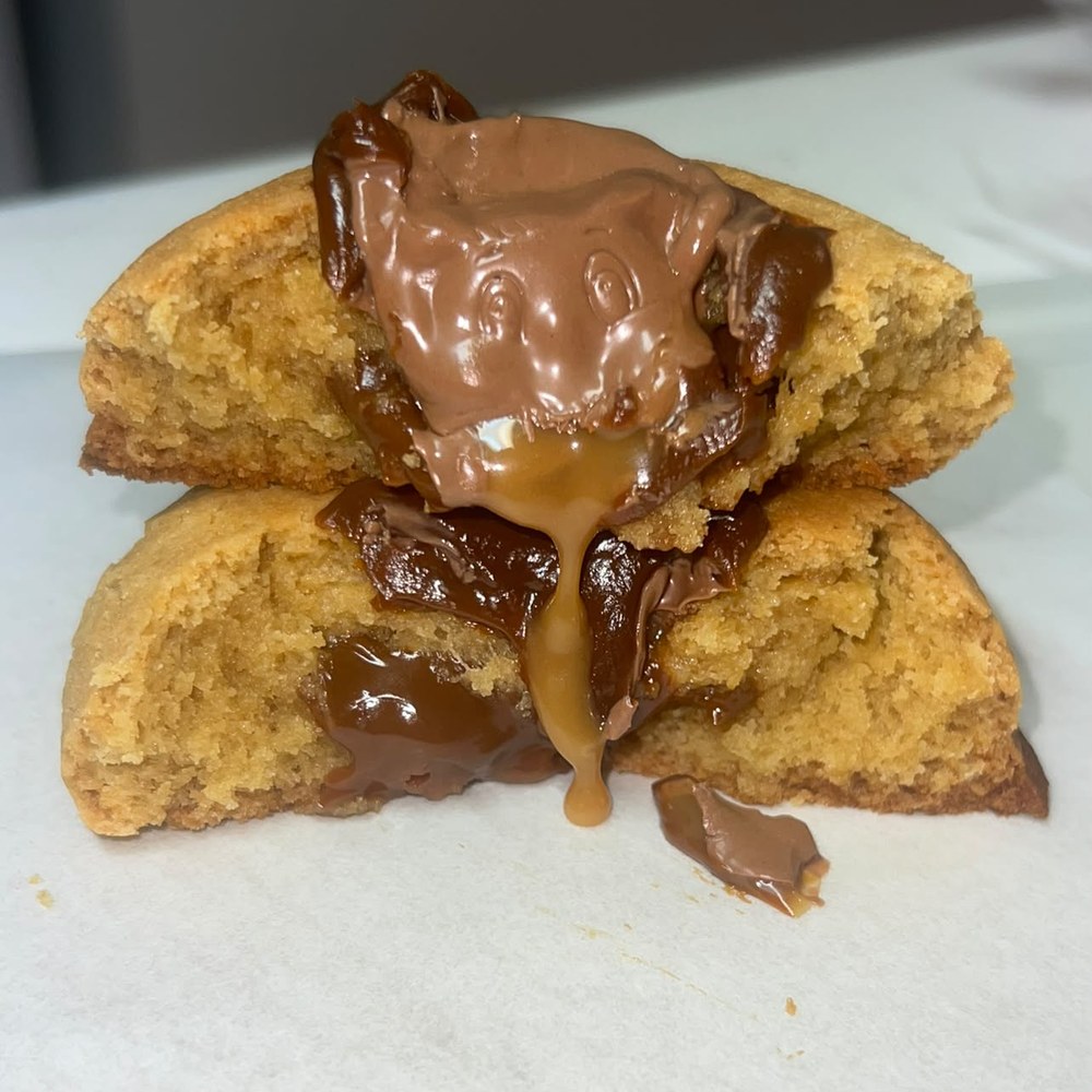 Salted caramel cookie broken open with caramel dripping from the middle