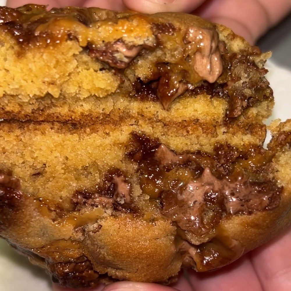 Warm cookie pulled apart to show a gooey chocolate and caramel centre