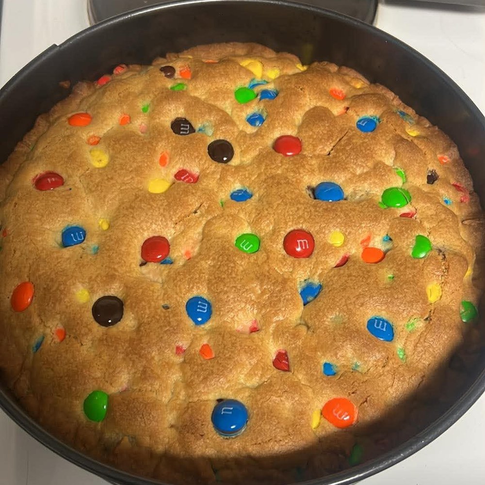 Large round cookie cake baked in a tin and studded with chocolate candies